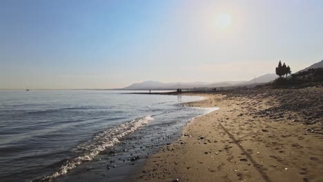 forward dolly shot of the beach shoreline, knee level, at marbella, spain