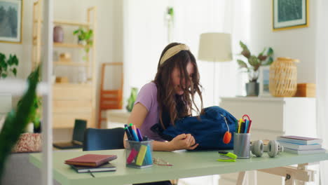 chica feliz desempaqueta su mochila de la escuela en el escritorio