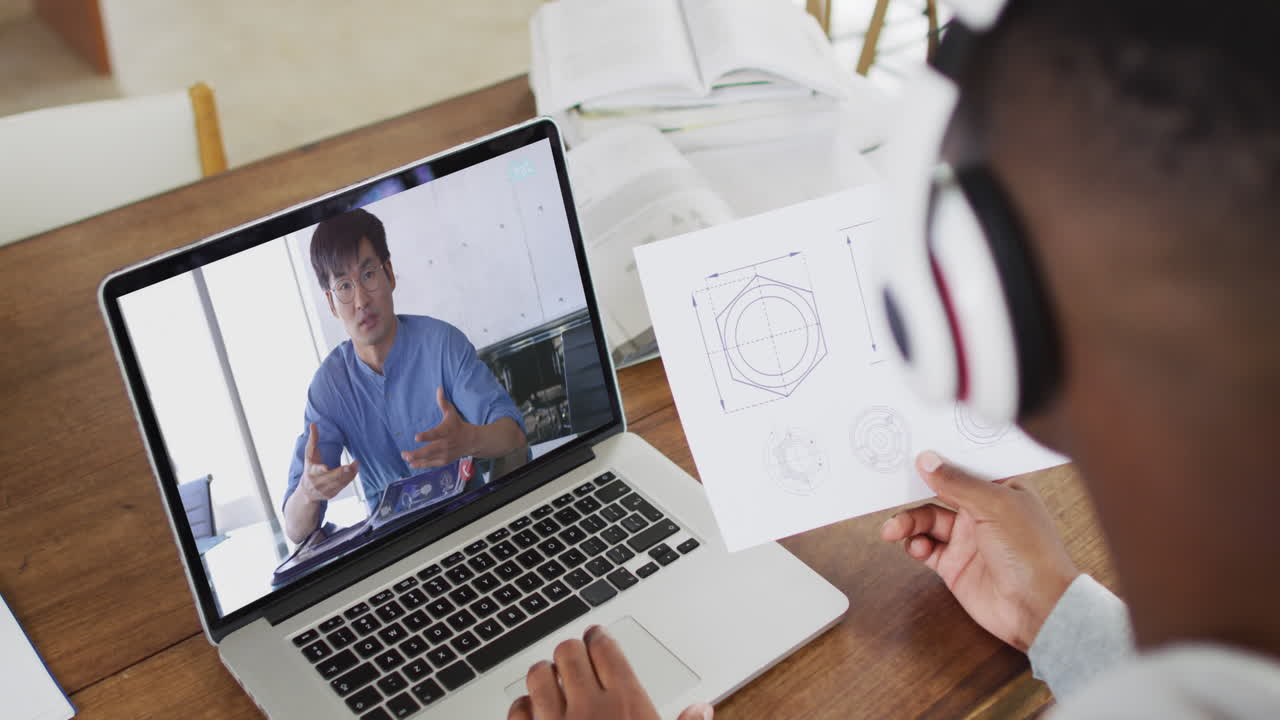 hombre de negocios afroamericano sentado en un escritorio usando una computadora portátil haciendo una videollamada con un colega masculino