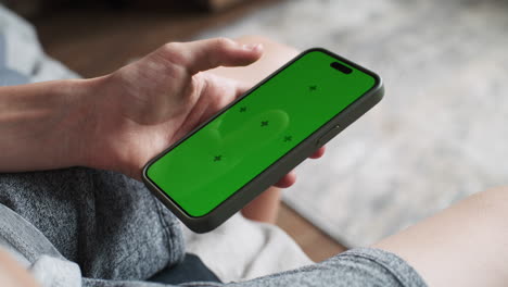 person using a smartphone with a green screen
