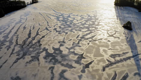 drone video of beautiful patterns on an ice covered lake by sunset