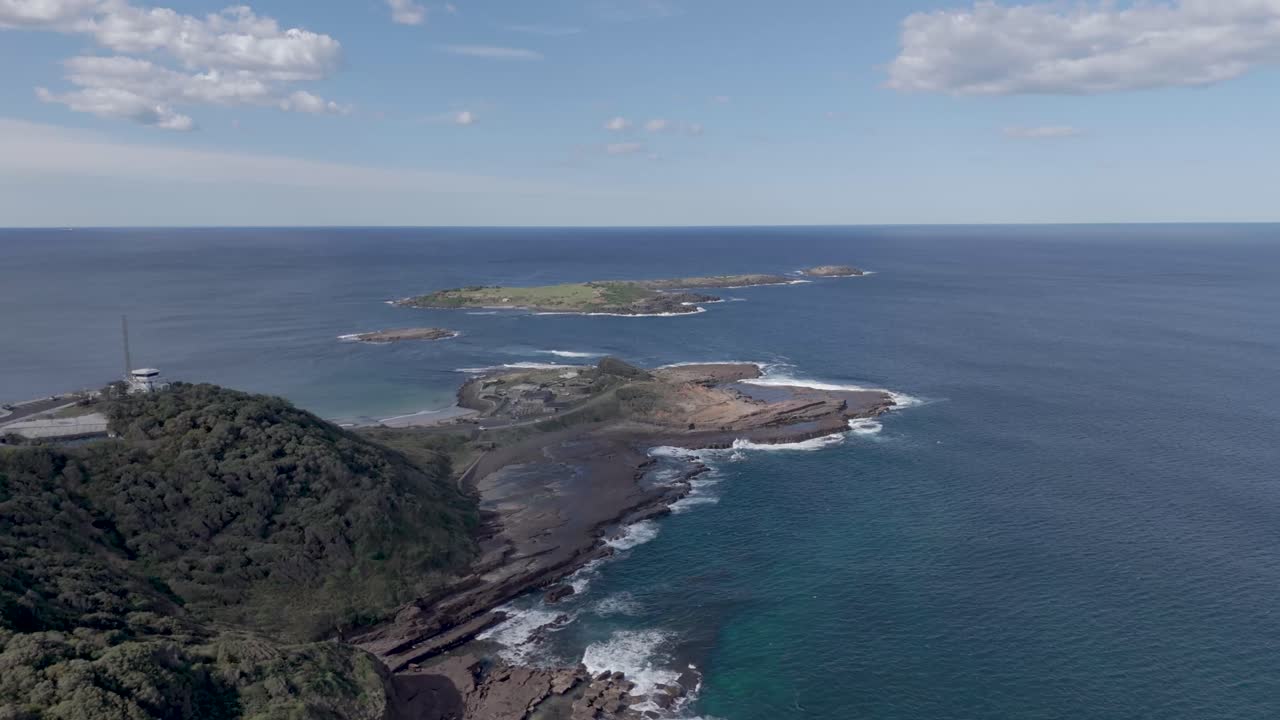 dolly aéreo a lo largo de acantilados volcánicos dentados con láminas de roca resbaladiza a lo longo de la costa a la isla baja en port kembla nsw australia
