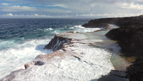 pacific ocean waves crash against rocks forming natural pools at cap des pins