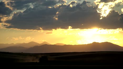 cosechadora en la zona rural de colorado, en un contexto de montañas y puesta de sol