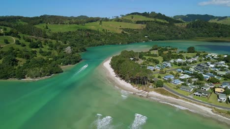 boat driving down purangi estuary along the coromandel peninsula