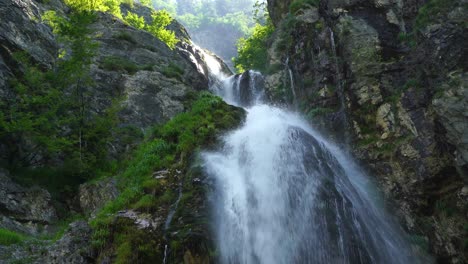 water stream falling from rocks on mountains slope and green vegetation in theth, albania