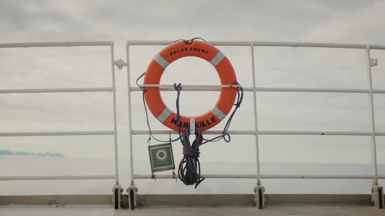 Salvagentte montato sulla ringhiera di una nave con il mare Artico calmo sullo sfondo.