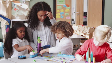 Eine-Kleinkindlehrerin-Hilft-Kindern-Bei-Der-Verwendung-Von-Konstruktionsspielzeug-Im-Klassenzimmer