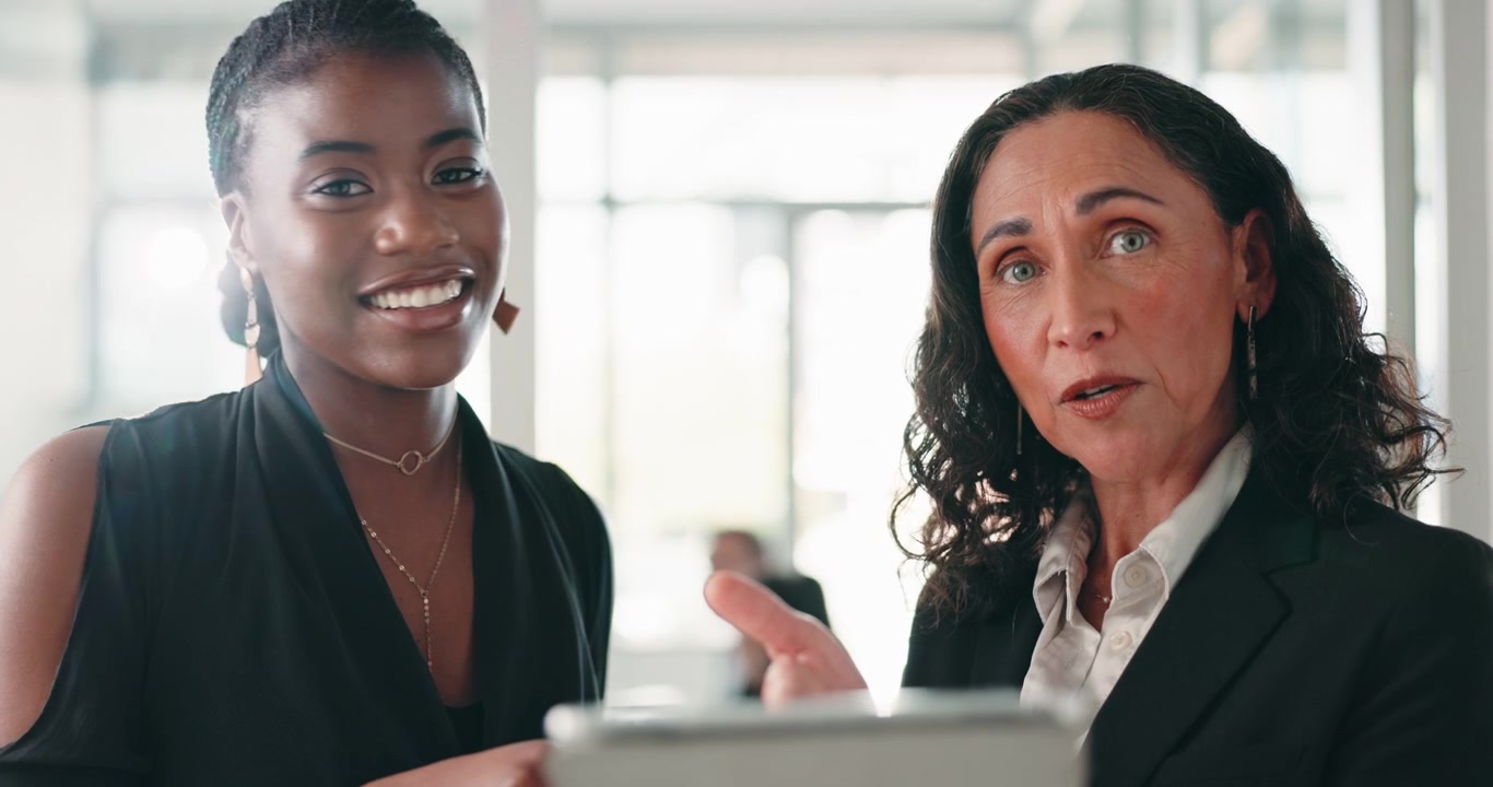 Due donne d'affari professioniste che discutono di lavoro su un tablet in ufficio