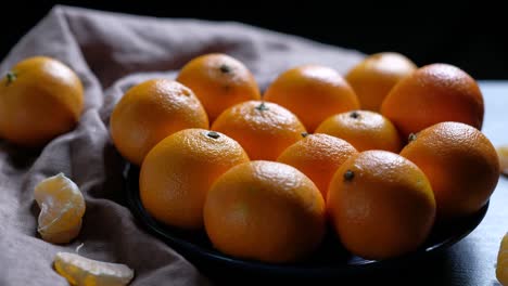 pile of unpeeled round ripe orange mandarin in a plate