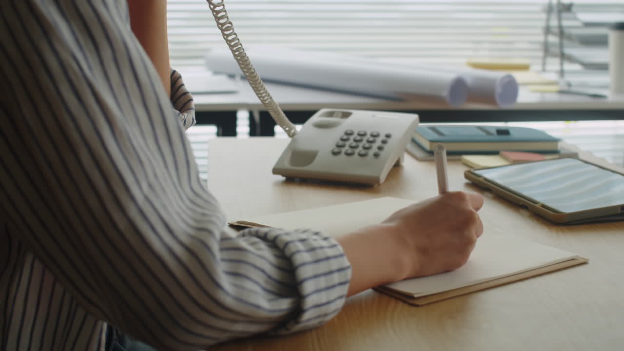 Female Manager Talking on Landline Phone and Making Notes