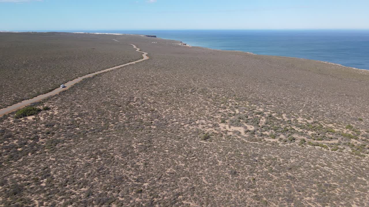 drone aéreo de una furgoneta conduciendo en una carretera de campo por un hermoso océano
