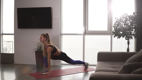 young fit female in sportswear doing stretching lunge exercise indoor, home interior. activity and healthy lifestyle. side view. slow motion