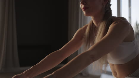 close-up yoga training in the hall with large windows and sunlight passing through the frame. a woman trains in the gym on a mat