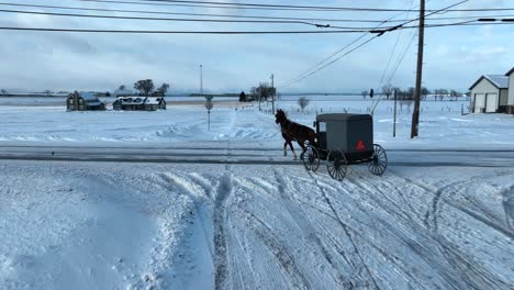 Toma-Aérea-De-Seguimiento-De-Un-Caballo-Y-Un-Buggy-En-Un-País-Amish-Cubierto-De-Nieve.