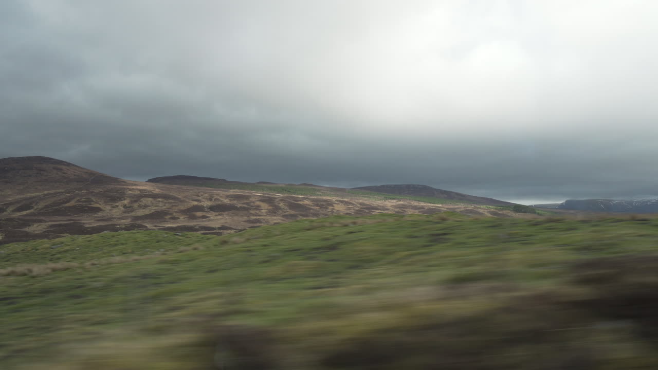 movimiento disparado desde el vehículo con primer plano pasando por muy rápido y montañas y valles en el fondo en la maravillosa luz del atardecer con buenas nubes en escocia