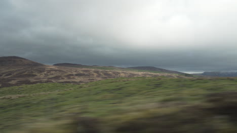 moving shot from vehicle with foreground passing by very fast and mountains and valleys in the background in wonderful sunset light with nice clouds in scotland