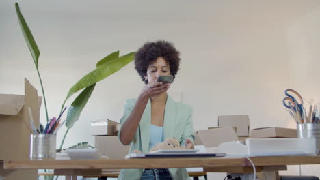 jovem empresária negra de casaco azul tirando foto com telefone para um ursinho de pelúcia