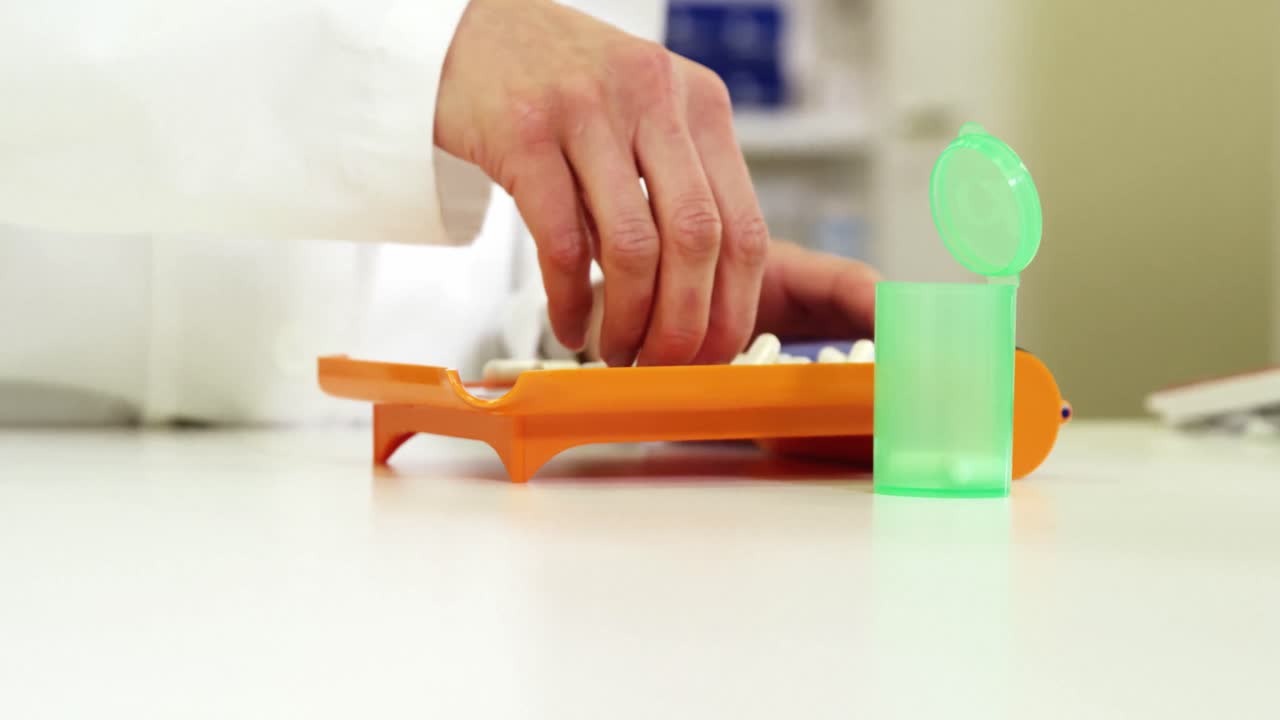 farmacéutico poniendo píldoras en el recipiente en la farmacia