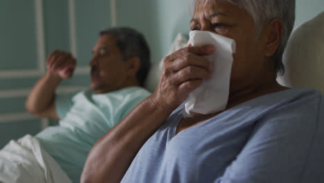 senior mixed race couple both ill in bed