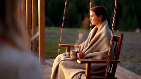 woman enjoying a coffee on a porch swing at sunrise