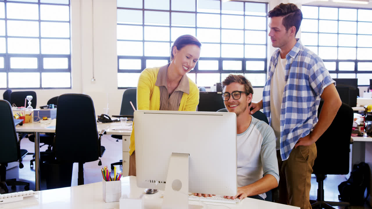 colegas mirando la computadora y discutiendo entre sí