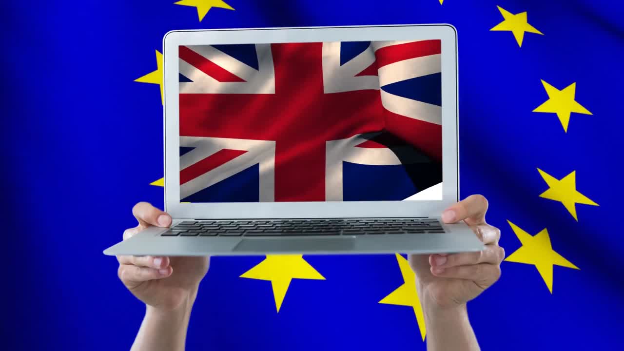 dos manos sosteniendo una computadora portátil con la bandera británica en pantalla completa