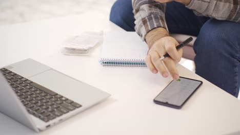 man looking at bills at home calculating with calculator.