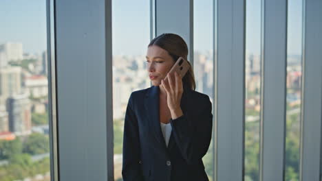 Woman boss talking cell at panoramic window. Corporate professional making call