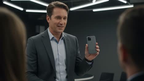professional man presenting a smartphone in a modern meeting environment, engaging audience with technology and communication insights.