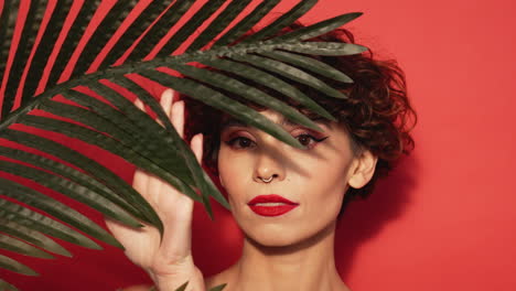 mujer de cabello rizado y hoja de palma