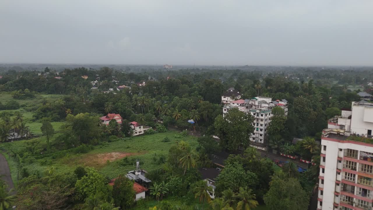 Wide panoramic drone footage capturing a lush tropical town surrounded by coconut trees and vegetation, taken after a refreshing rain shower