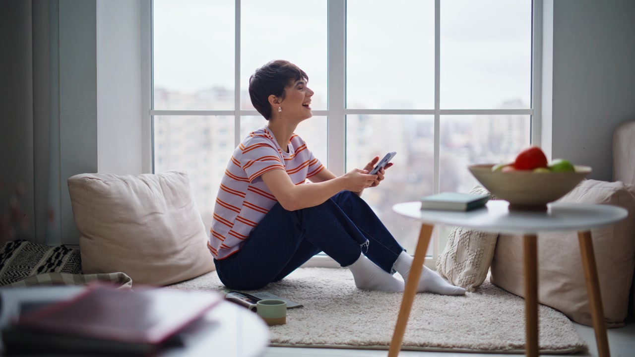 Donna si gode contenuti di intrattenimento sullo smartphone seduta in un lussuoso interno domestico.