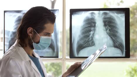 Doctor-with-face-mask-checking-carefully-X-ray-film-for-treatment-plan