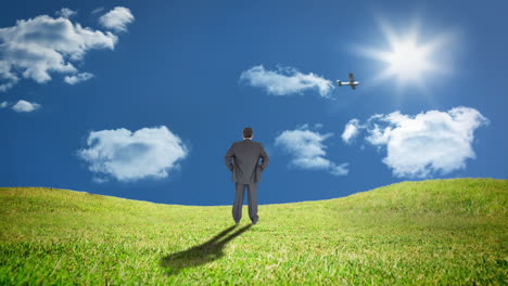 Rear-view-of-businessman-standing-in-grass-watching-plane