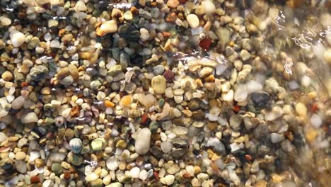 Small-beach-pebbles-under-sea-wave-top-view