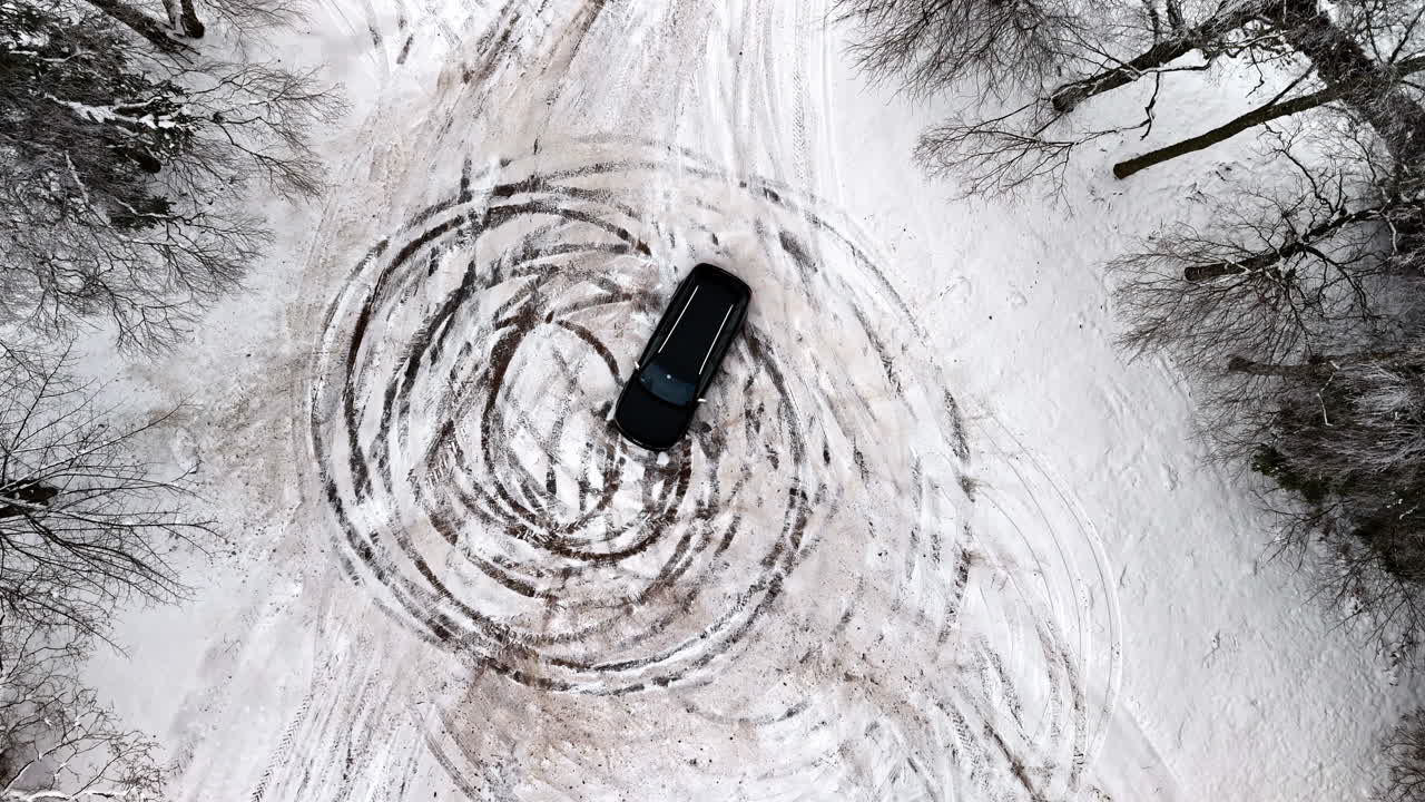 Top view of a vehicle doing donuts on a snow covered road