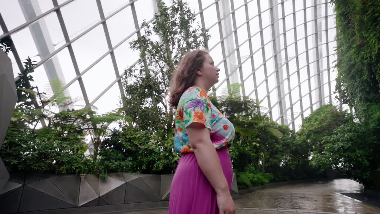 인쇄된 드레스를 입은 여성이 싱가포르의 구름 숲의 식물원 전망을 즐기고 있습니다.