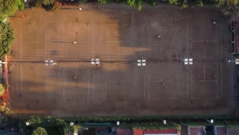 aerial view of people playing tennis on multiple clay courts
