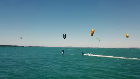 kite-surfisti professionisti per sport acquatici inseguiti da droni durante la splendida luce del giorno naturale con cielo blu e acqua turchese sull'oceano aperto a città del capo, sud africa