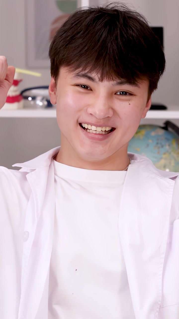 A happy student cheers and pumps his fist while wearing a white lab coat.