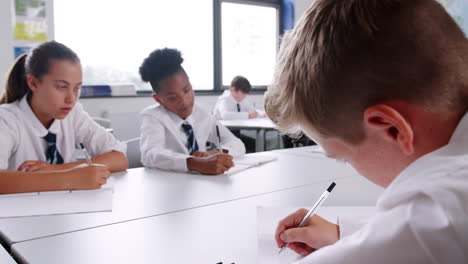 Gruppe-Von-Gymnasiasten-In-Uniform,-Die-An-Schreibtischen-Im-Klassenzimmer-Arbeiten