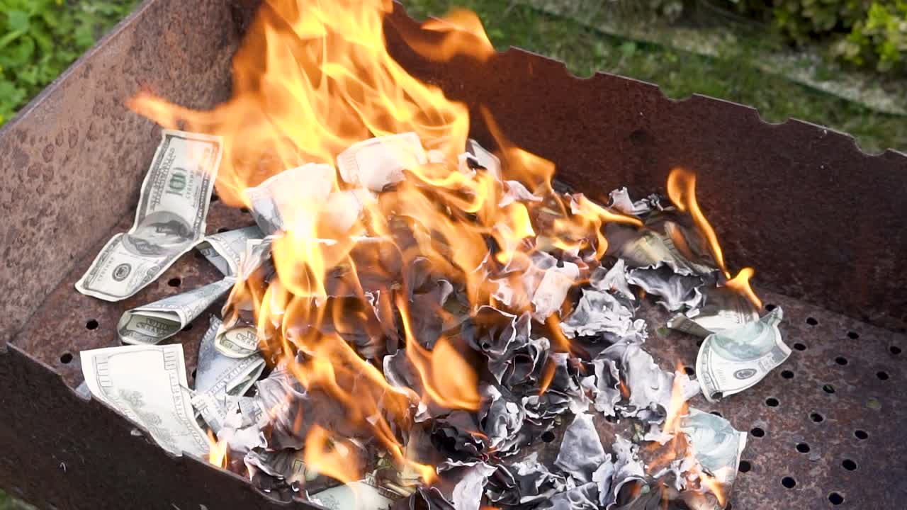 Burning counterfeit dollars in the grill. Flames from burning a pile of paper. Slow motion