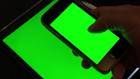 hombre en forma desplazándose a través de una diapositiva de algunas imágenes en su teléfono verde después de revisar su ipad verde mientras tomaba un descanso del trabajo