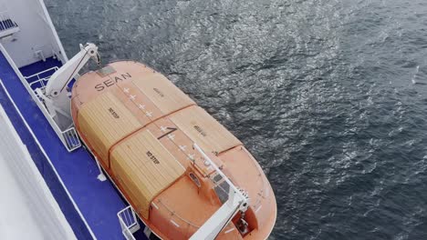 Orange-lifeboat-on-a-ferry-while-traveling-to-safety