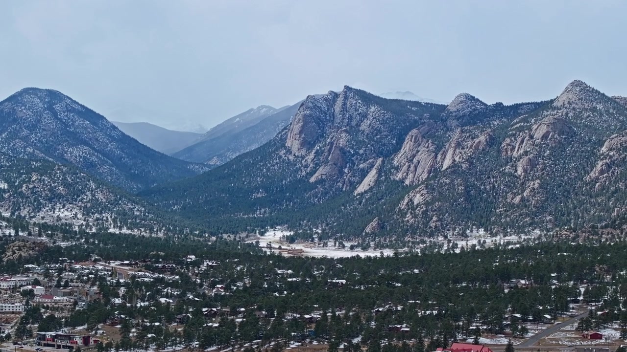 La città di Estes Park e la foresta circostante con le Montagne Rocciose coperte di neve, panoramica aerea con drone.