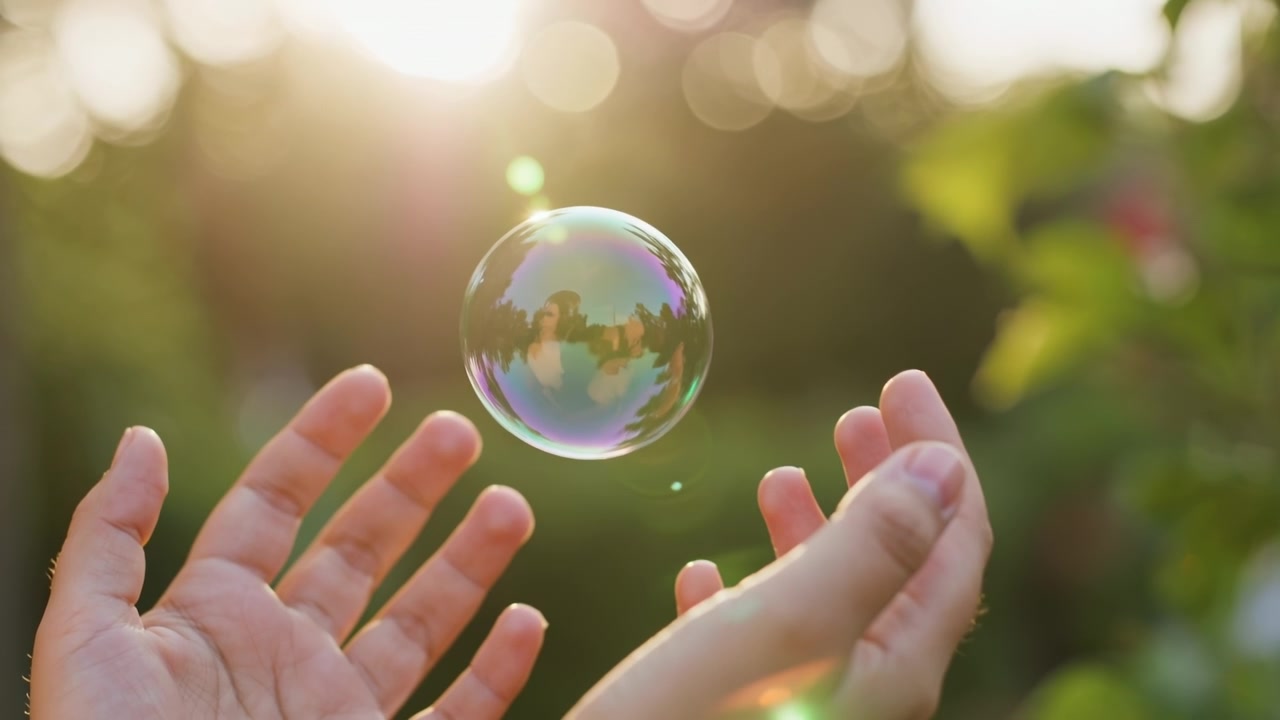 Bolla di sapone che fluttua nell'aria con mani che si protendono per afferrarla in un giardino