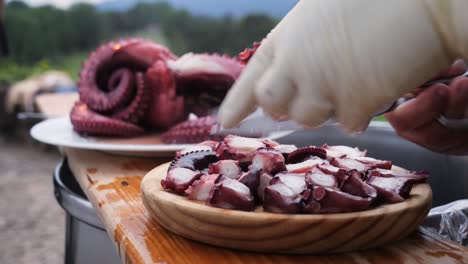 detail of the hands of a cook cutting an octopus leg with scissors to serve in "pulpo a feira" typical galician tapa