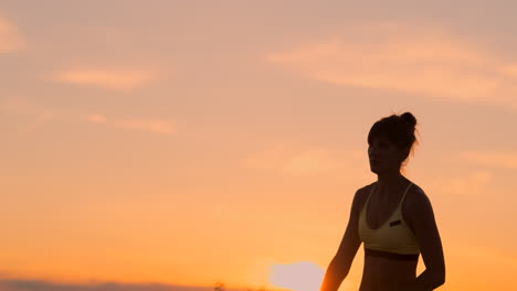 jugador de voleibol femenino del plan medio al atardecer poniendo una espalda en la pelota en cámara lenta.