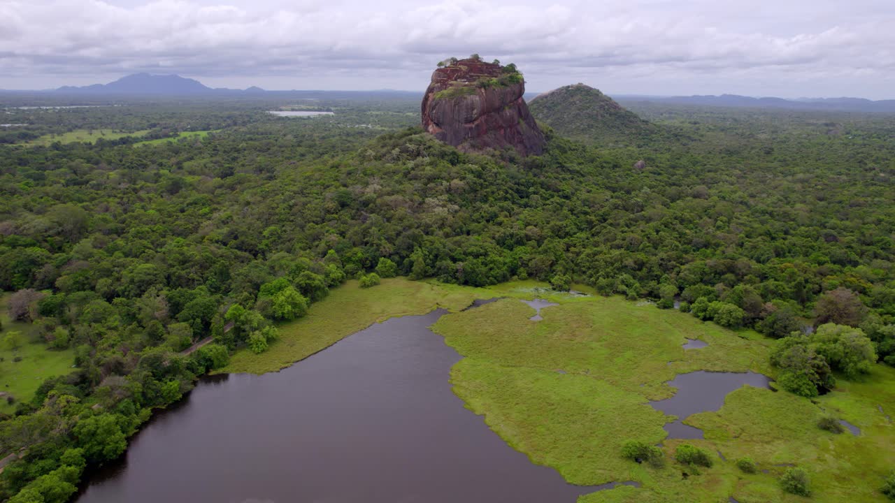 Lion Rock emerging from dense rainforest near calm reservoir